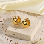 pair of polished dome huggie earrings displayed on pale stone