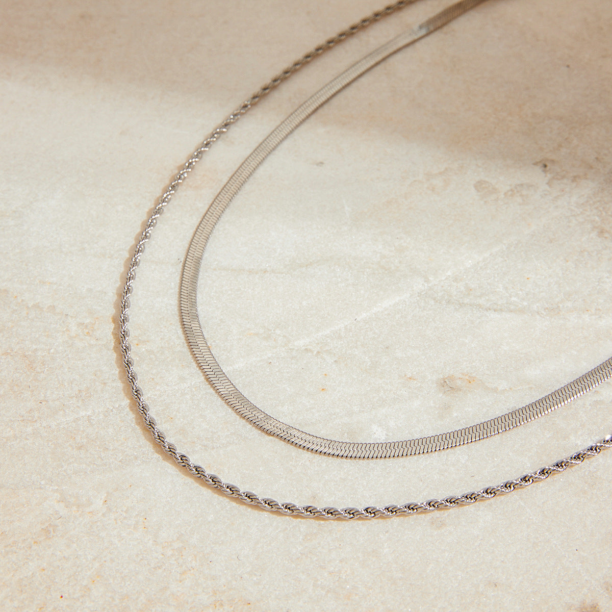 Two contrasting chain textures arranged on a pale surface