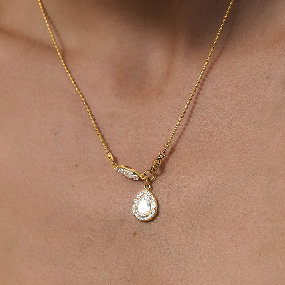 Pear halo necklace worn at the neckline