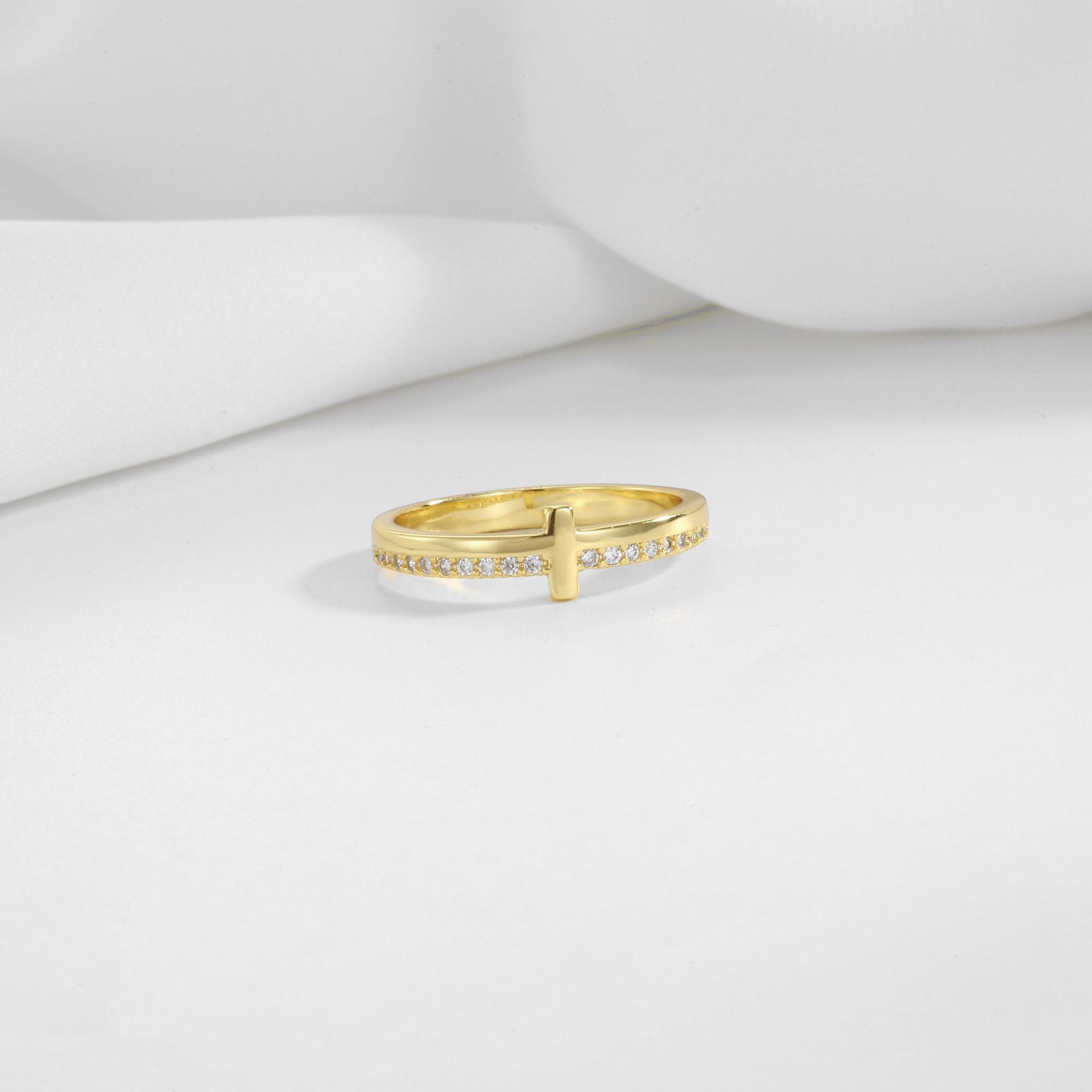 gold plated brass cross ring displayed on white folds