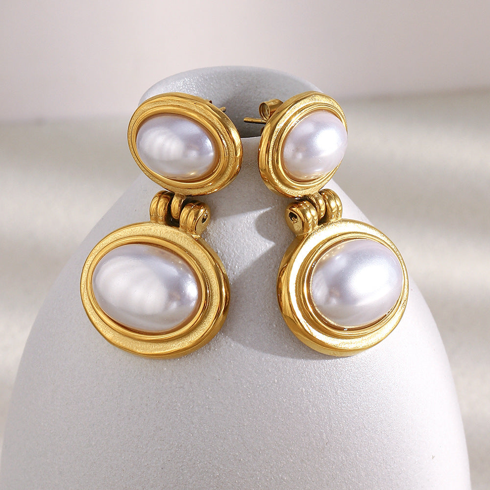 pair of gold plated imitation pearl drops on a curved white display