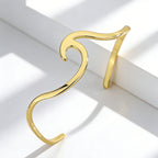 upright view of asymmetrical wave open cuff with curled end