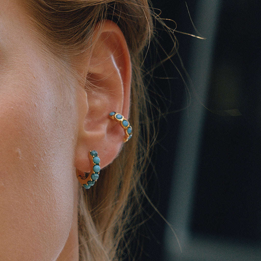 Model wearing gold-tone huggie earrings with white imitation pearls