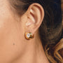gold plated oval stone huggie earrings worn on ear