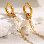 gold plated asymmetric pearl chain huggie earrings on a neutral surface