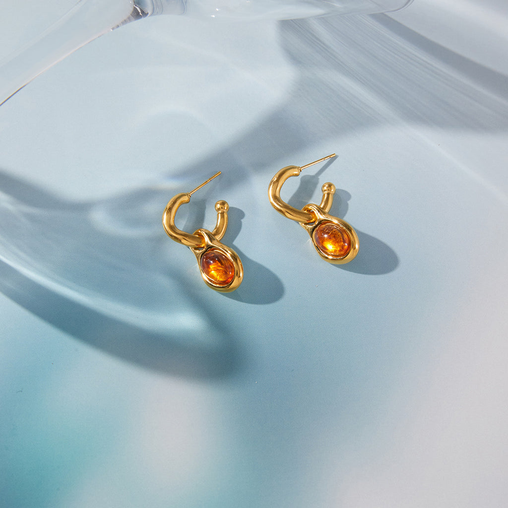 pair of amber-color resin drop hoops on blue reflective surface