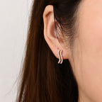 Gold tone wave huggie worn at the earlobe