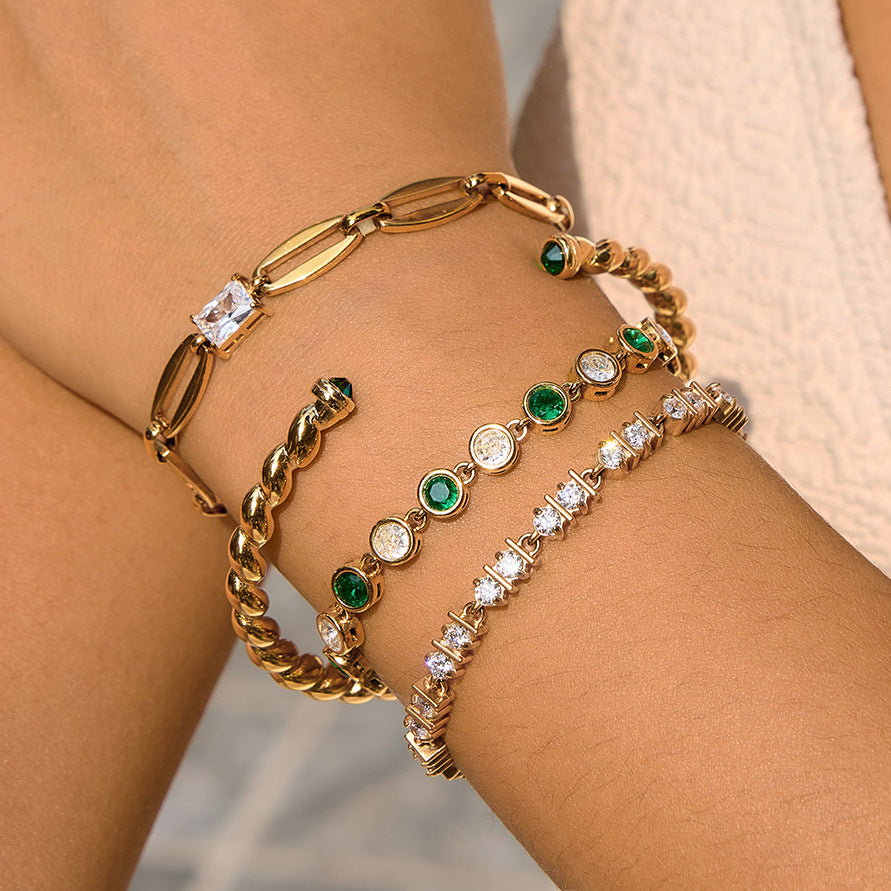 Four gold tone stainless steel bracelet designs stacked on a wrist