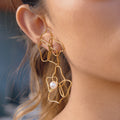 gold plated open floral pearl-style drop earring worn on ear