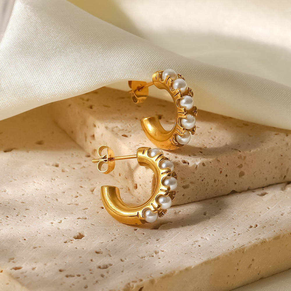 asymmetric gold plated pearl hoop earrings on cream fabric