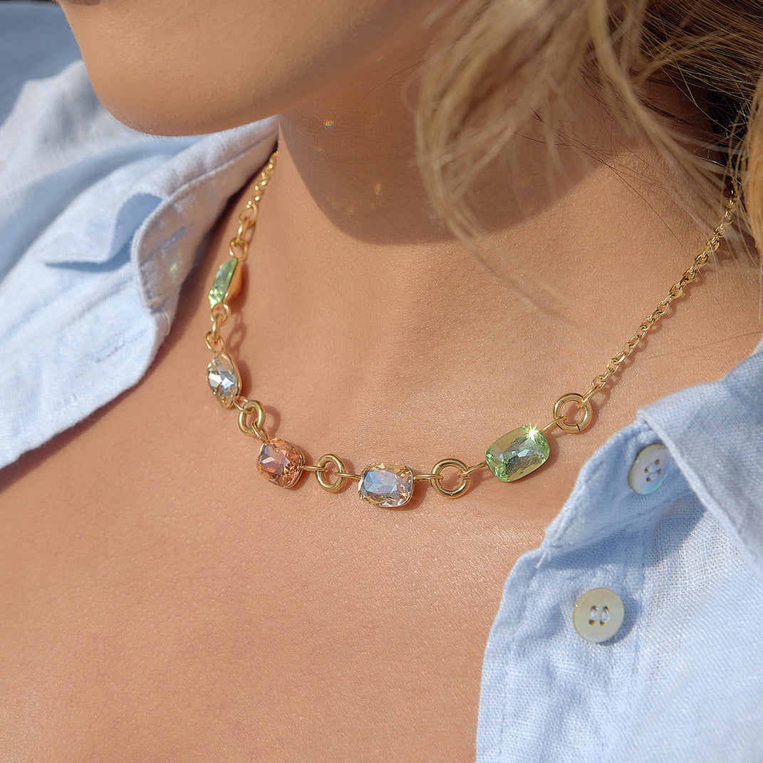 Close wearing view of green, clear and peach-colored stones joined by round links