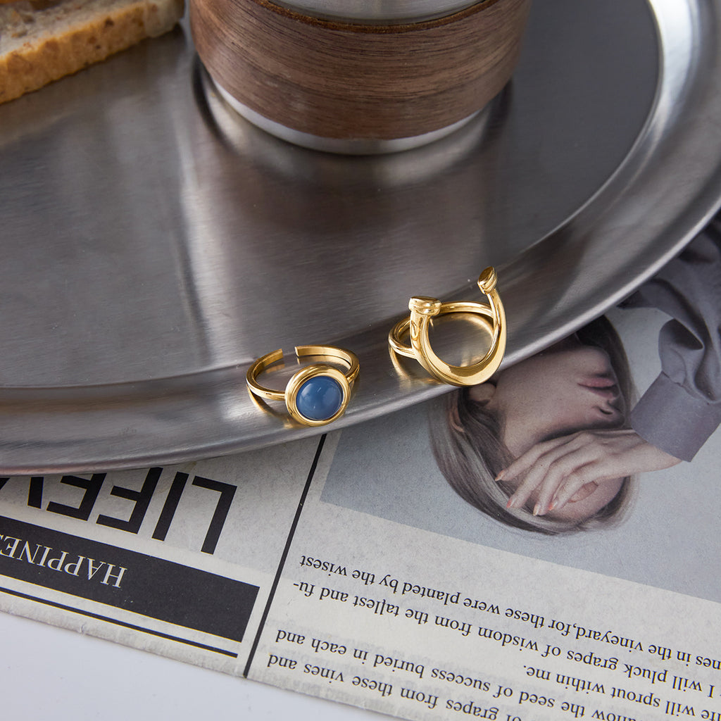 Front and rear views of the blue resin horseshoe ring beside a coffee saucer