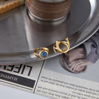 Front and rear views of the blue resin horseshoe ring beside a coffee saucer