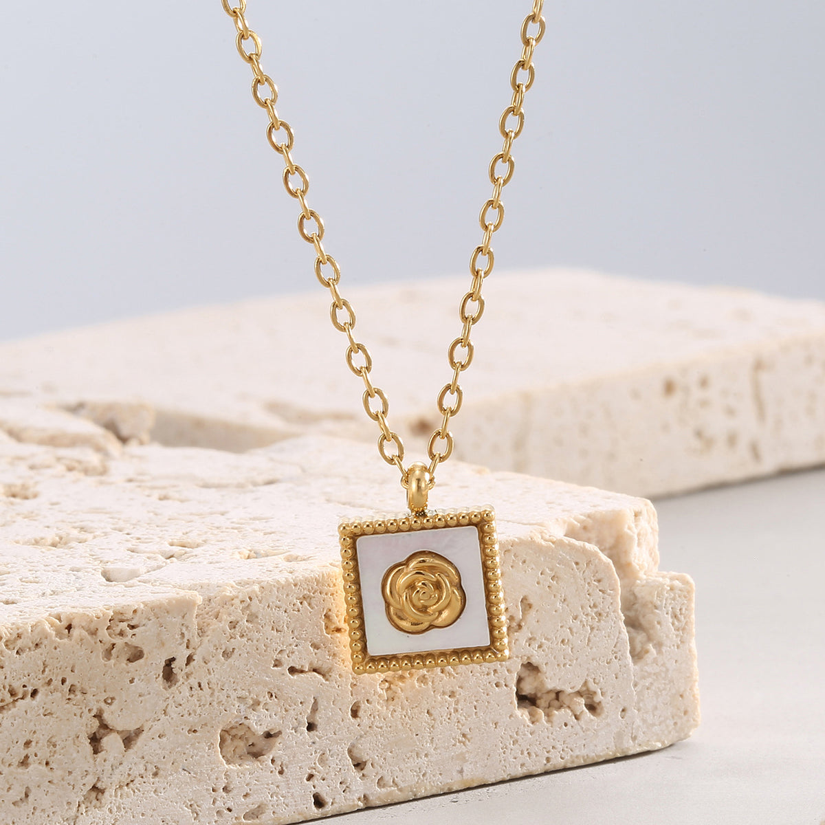 angled rose medallion pendant displayed on pale stone