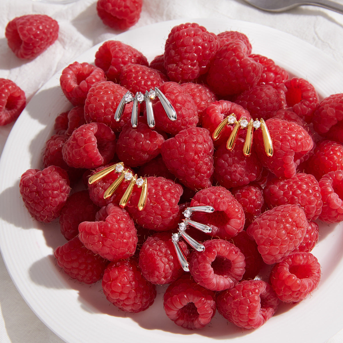 Gold and steel color stud earrings on raspberries