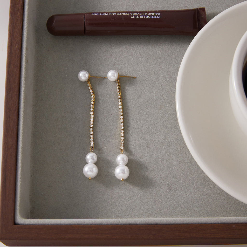 Pair of glass pearl drop earrings displayed in a tray