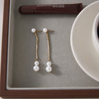 Pair of glass pearl drop earrings displayed in a tray