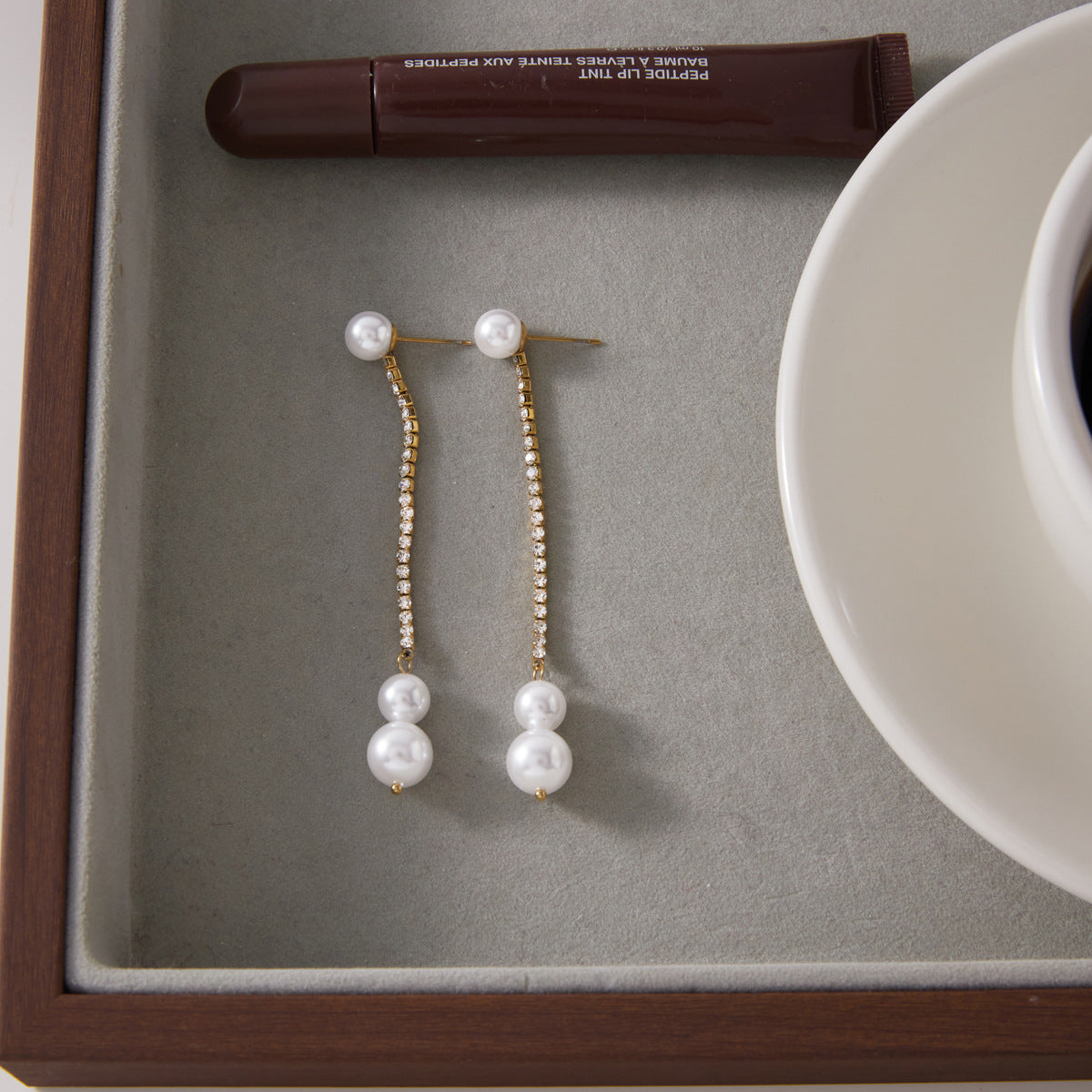 Pair of glass pearl drop earrings displayed in a tray