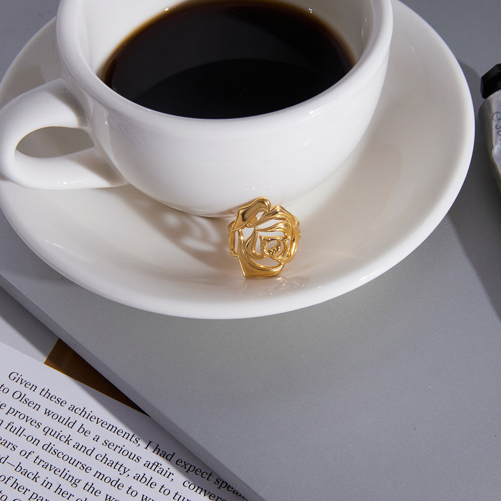 Sculptural rose ring displayed beside a coffee cup