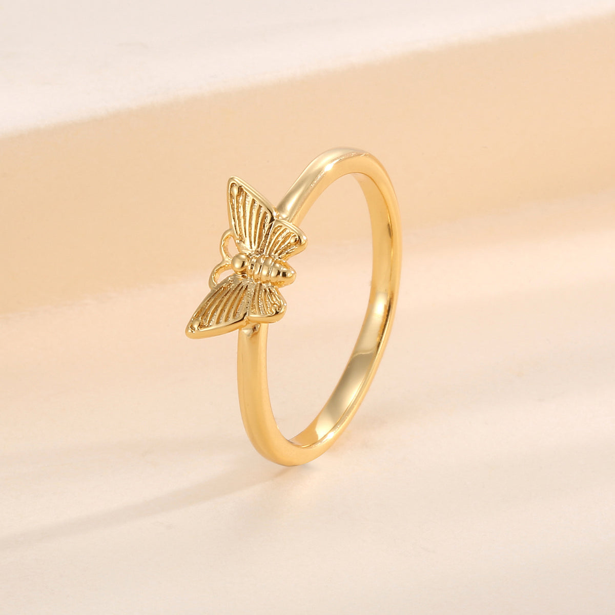 angled butterfly motif ring on a warm cream background