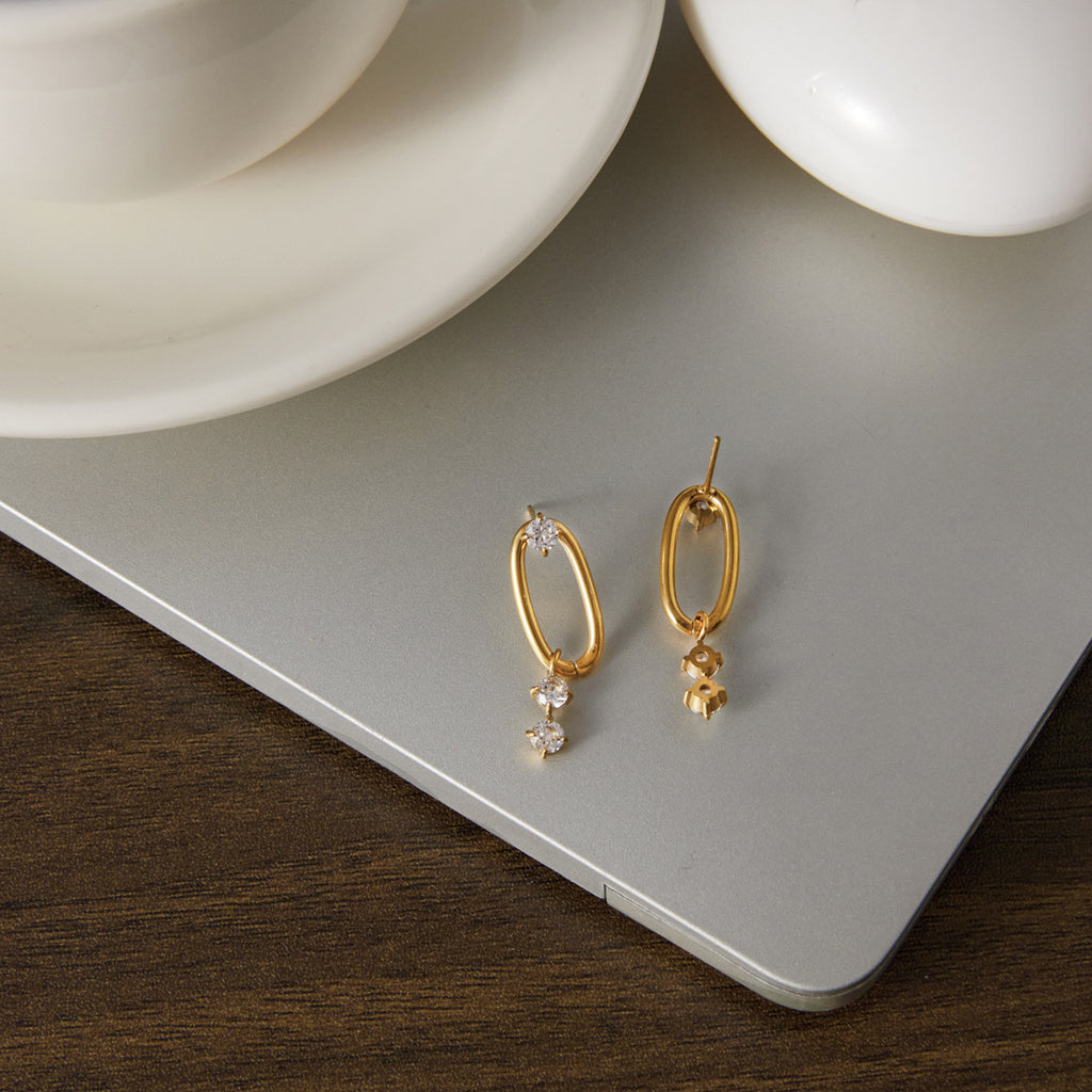 Pair of oval link earrings displayed on neutral board