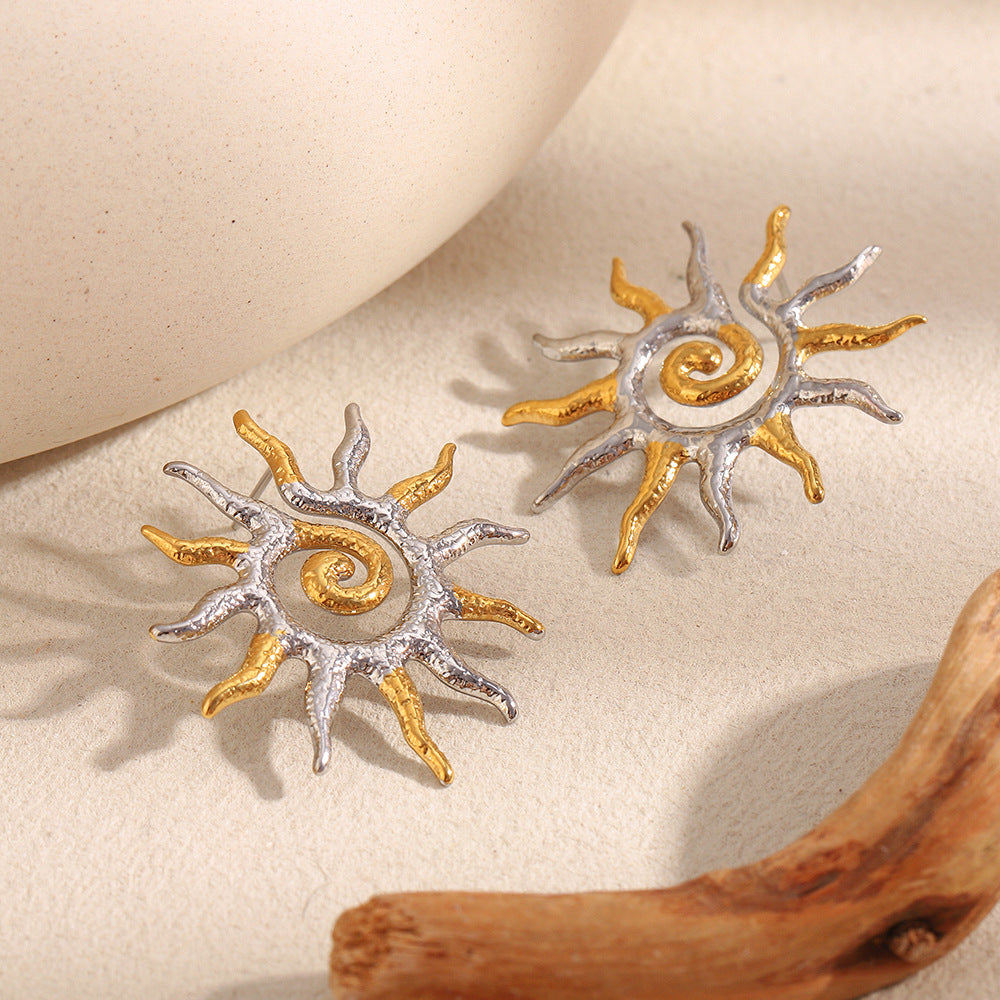 gold plated and silver-finish spiral sun earrings on cream fabric