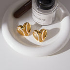 pair of gold plated stainless steel heart studs in a styled setting