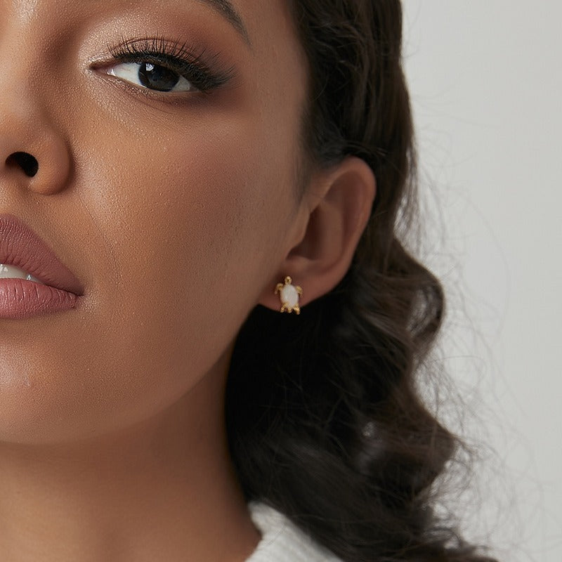 Opal sea turtle stud earrings shown on a model