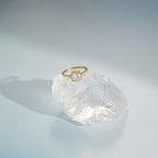 Gold tone halo ring displayed on a clear decorative stone