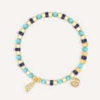gold plated shell-shaped charm bracelet with mixed blue beads on white