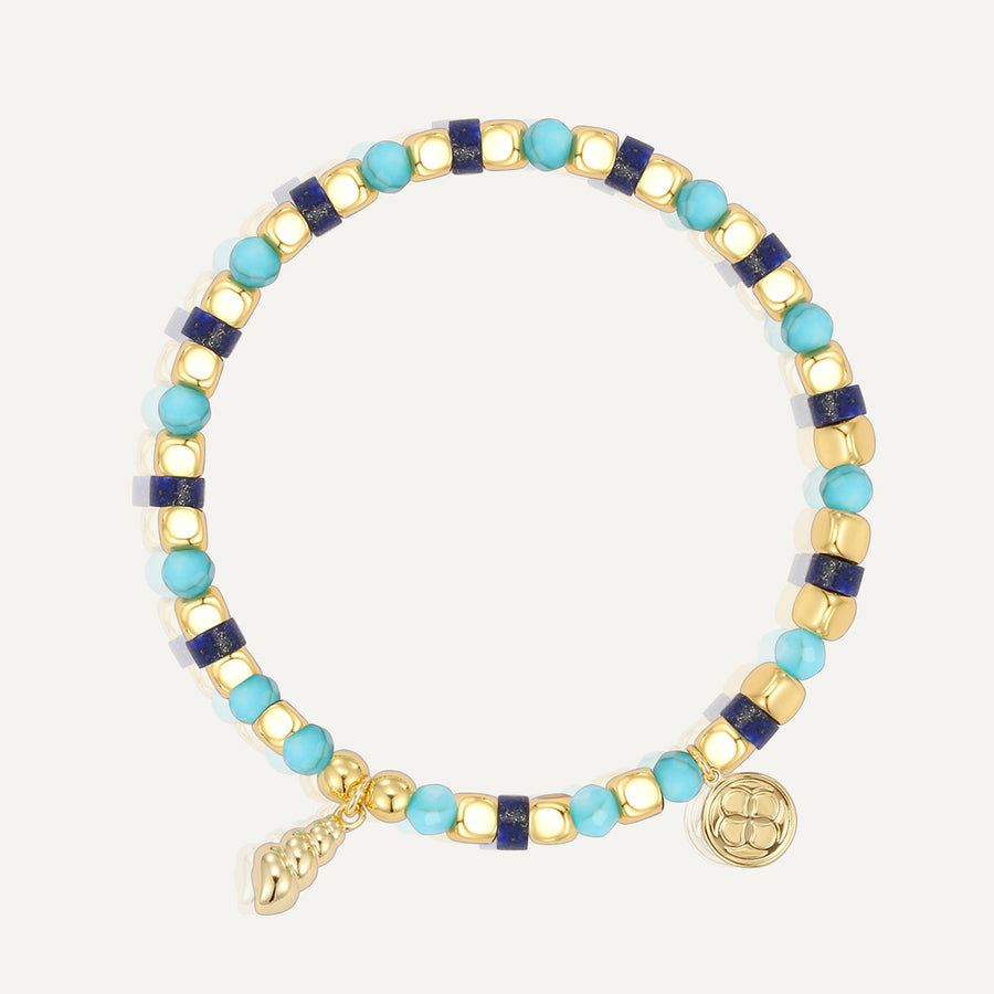 gold plated shell-shaped charm bracelet with mixed blue beads on white