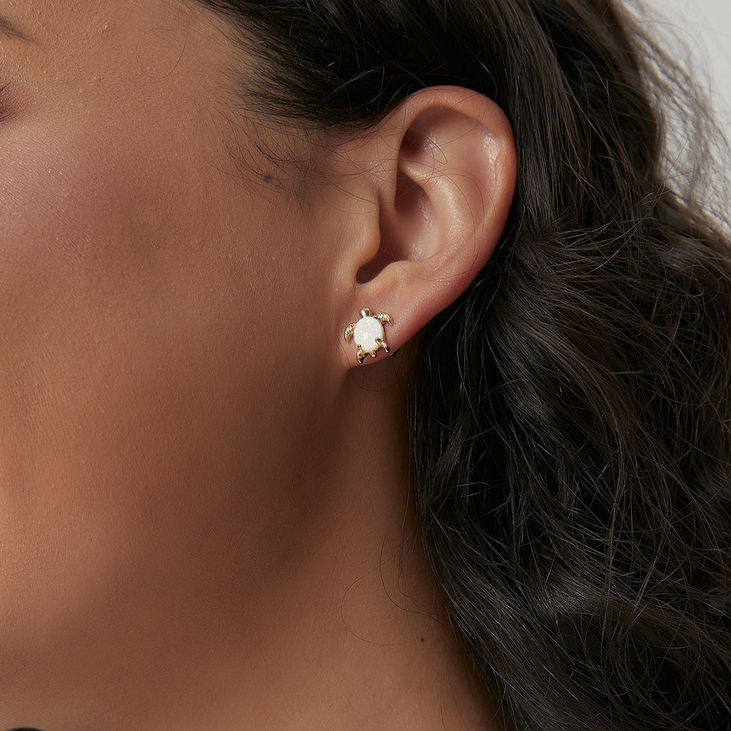 Gold plated opal sea turtle stud earring worn on the ear