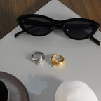 Gold and silver tone dome rings displayed beside sunglasses