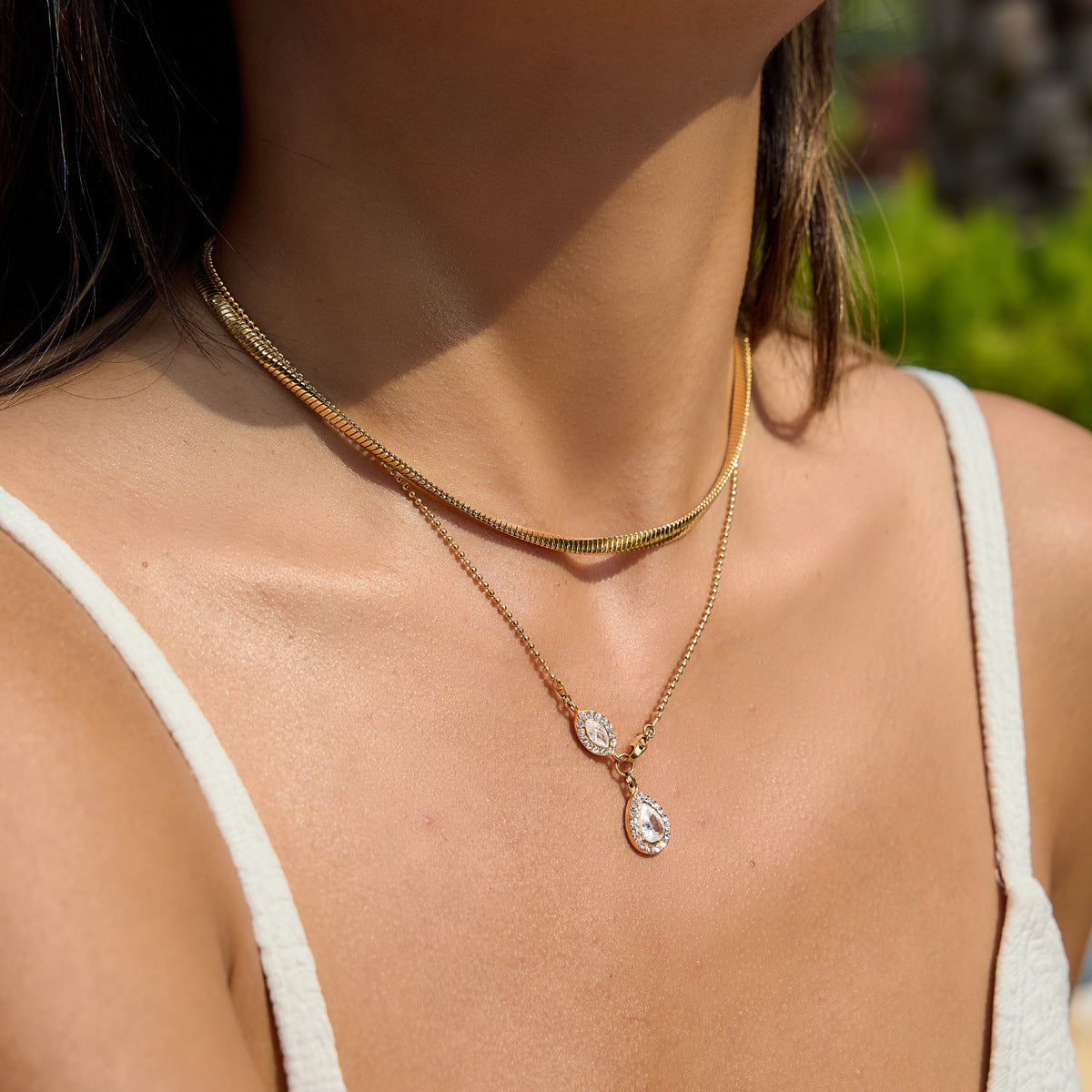 Gold tone snake chain necklace layered with a separate pendant necklace