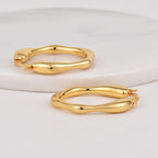 pair of irregular polished oval hoop earrings viewed from above