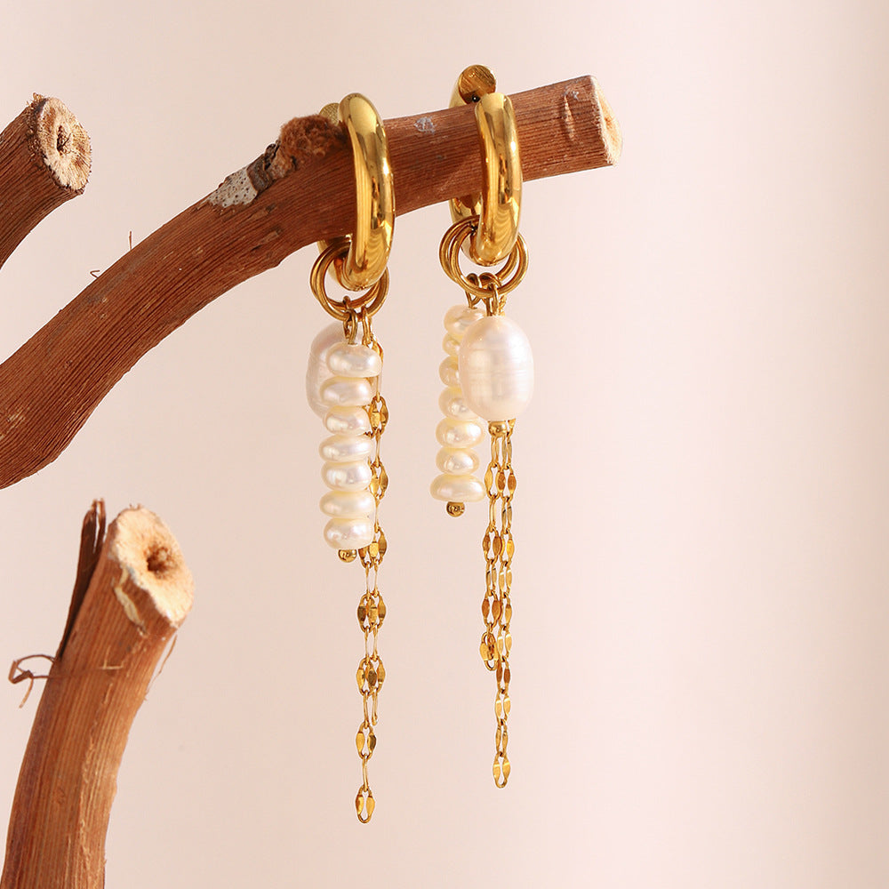 long pearl chain huggie earrings hanging from a natural wood branch