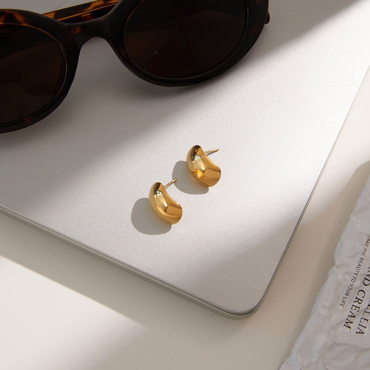 gold plated rounded dome earrings beside sunglasses