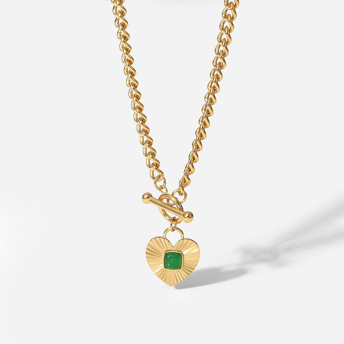 isolated chunky curb necklace with square green center stone