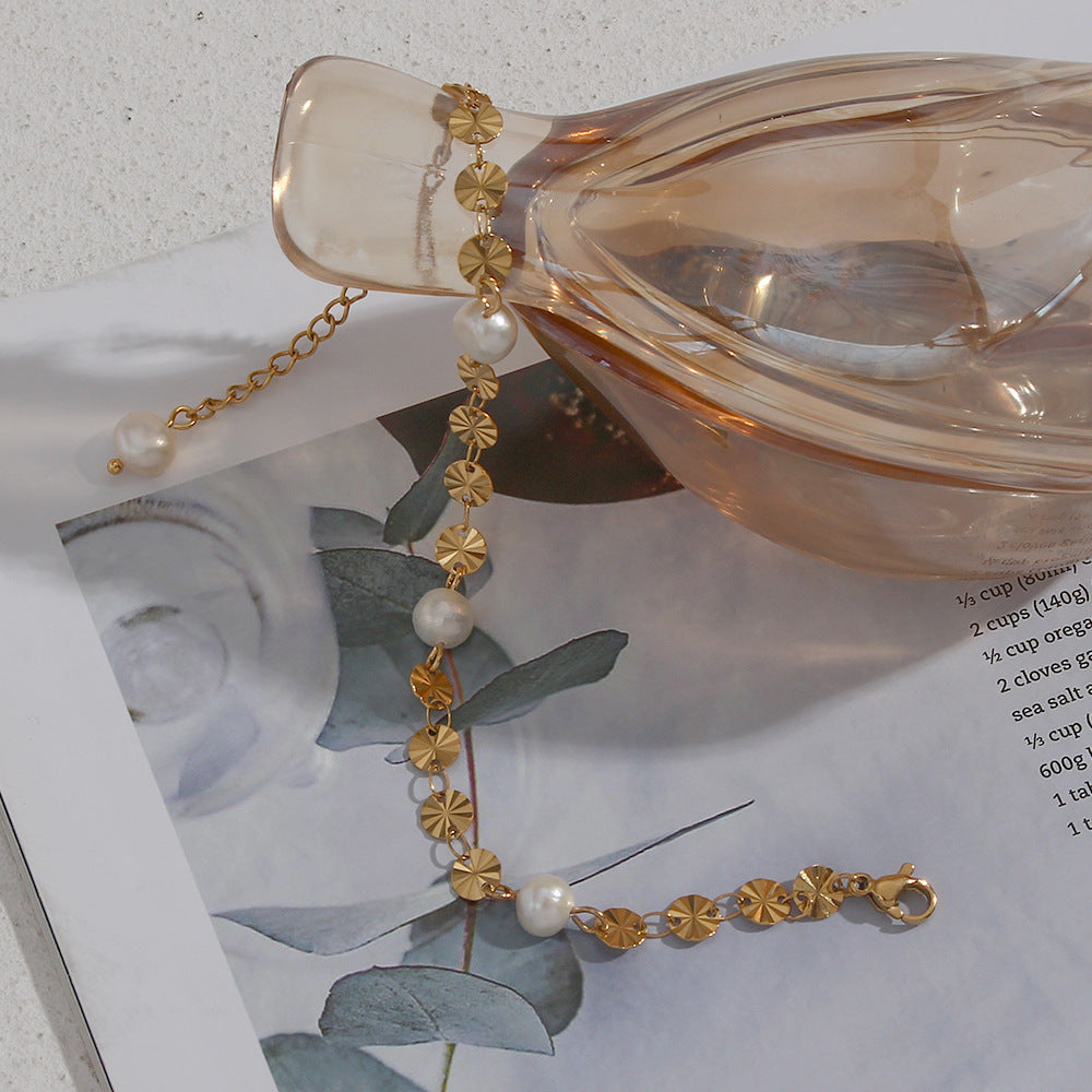 Sunburst disc and freshwater pearl bracelet draped over a glass prop