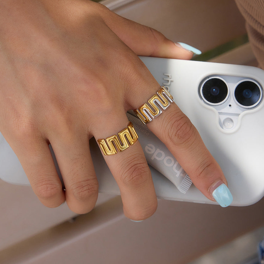 Geometric open rings shown on a hand holding a phone