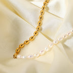 White bead and gold oval bead necklace worn at the collarbone