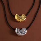Gold tone and silver tone spiral shell pendants on black cords