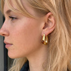 Brown resin accent U hoop earring worn on an ear