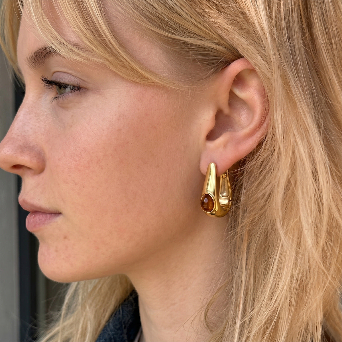 Brown resin accent U hoop earring worn on an ear