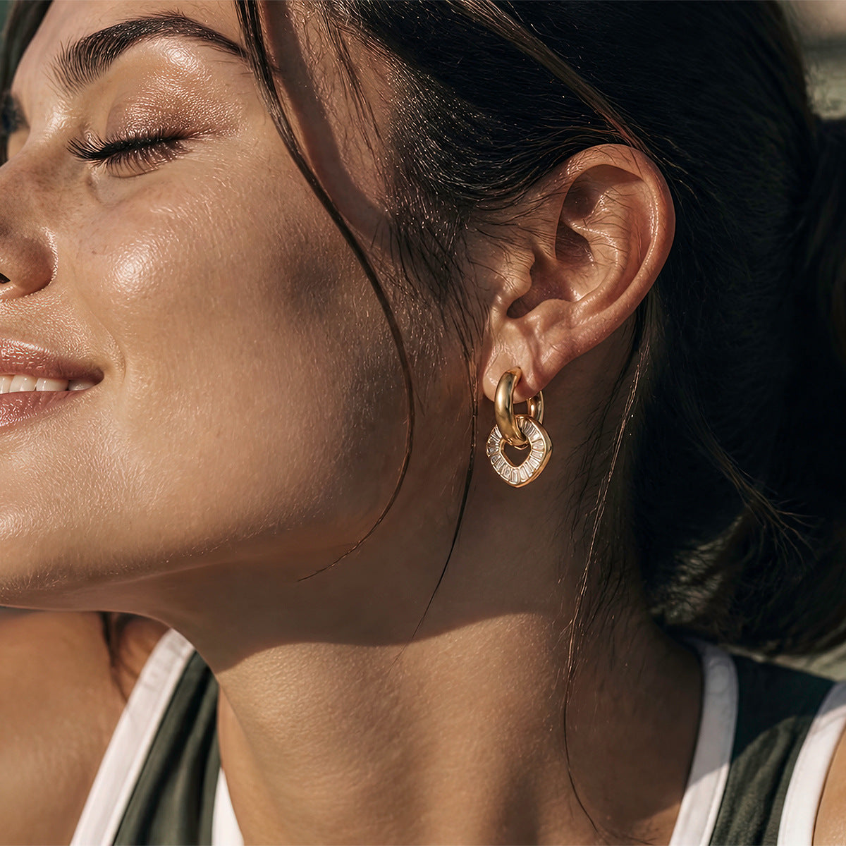 Gold tone open disc drop hoop worn on an ear