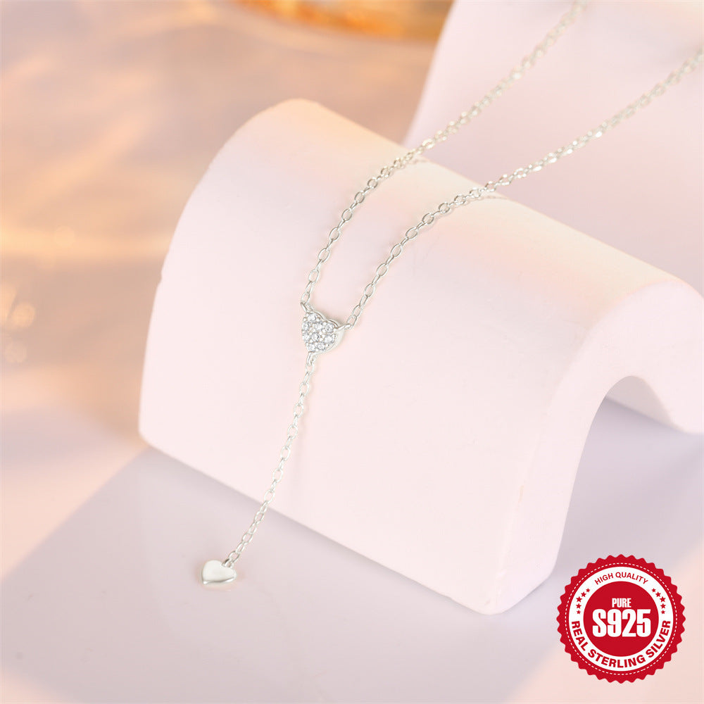 silver-finish heart Y necklace displayed on a curved stand