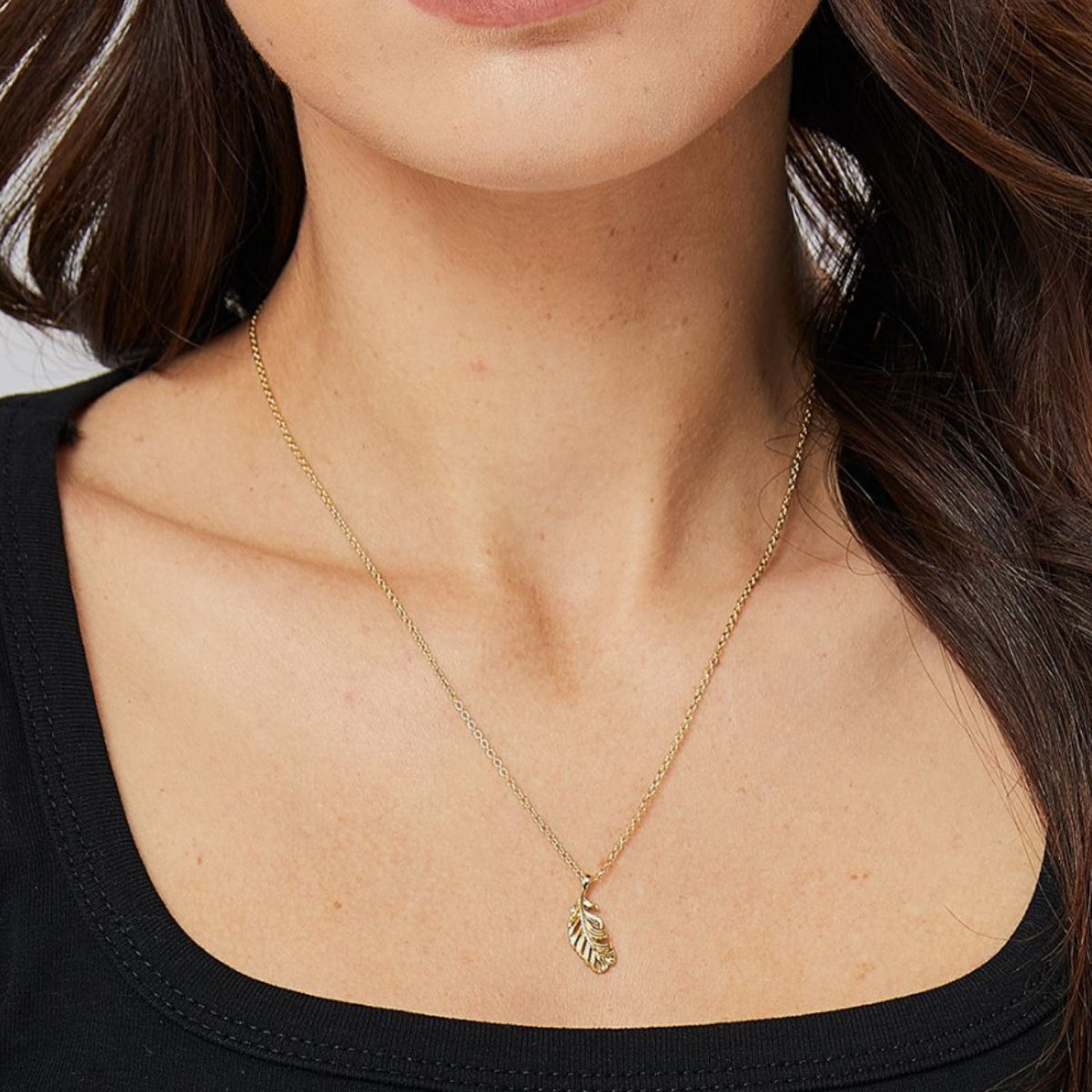 gold plated feather necklace shown at collarbone length