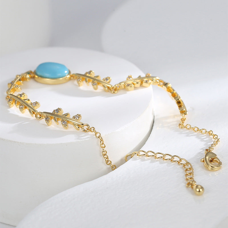 angled view of turquoise-color cabochon and clear leaf accents