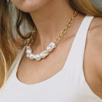 Asymmetric white bead and gold link necklace worn close-up