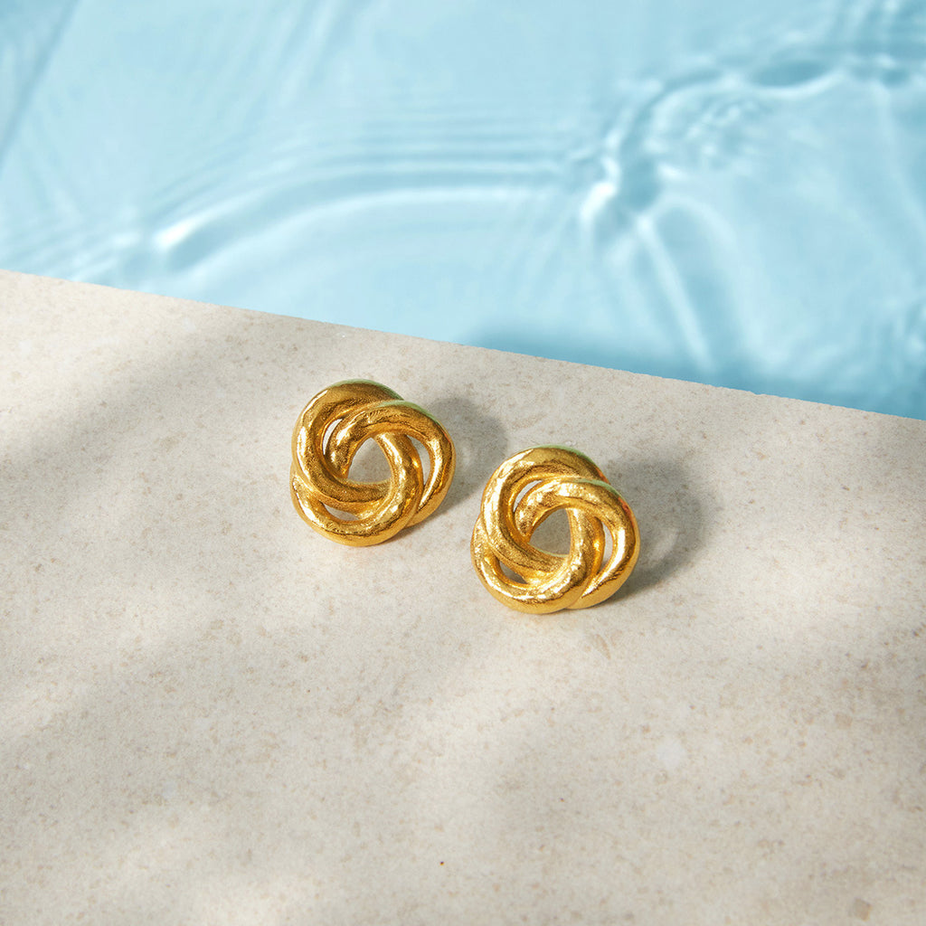 Gold-tone knot studs beside a pool